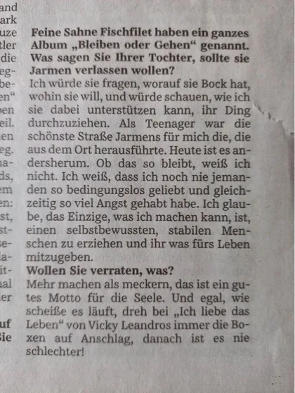 Fotografie einer Zeitungseite mit deutschem Text; oben ist die Überschrift „Feine Sahne Fischfilet haben ein ganzes Album ‚Bleiben oder Gehen‘ genannt.“ Mehrere Absätze in schwarzer Schrift auf hellgrauem Papier, linke Spalte eines weiteren Texts ist teils sichtbar und am rechten Rand fällt ein leichter Schatten auf.
