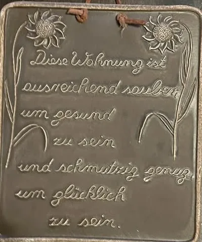 Schild mit Text "Diese Wohnung ist ausreichend sauber, um gesund zu sein und schmutzig genug, um glücklich zu sein"